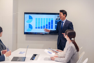 会議で資料を見ながらプレゼンをする中年のオフィスワーカー