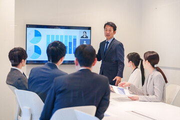 会議で資料を見ながらプレゼンをする中年のオフィスワーカー