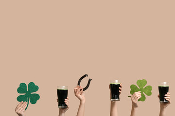 Many hands with beer and decorations for St. Patrick's Day on beige background