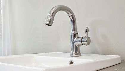 Chrome faucet on white sink against light-colored wall