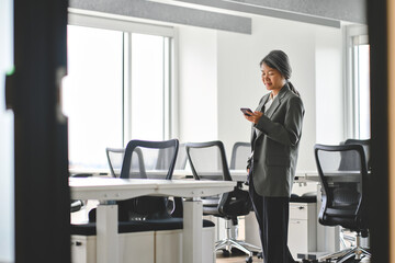 Busy middle aged Asian professional business woman company executive manager worker wearing suit...