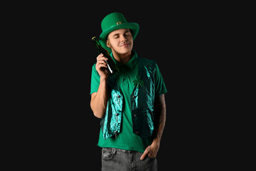 Happy young man in green clothes and with beer on dark background. St. Patrick's Day