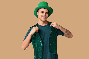 Happy tattooed young man in green clothes on beige background. St. Patrick's Day