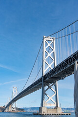 A large bridge spans a body of water, with a clear blue sky above