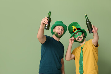 Young men in leprechaun hats with green beards holding bottles of beer on green background. St....