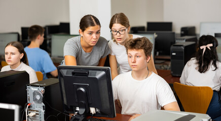 Fototapeta premium Young female teacher working with students in computer class of university