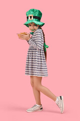 Funny girl with face painting, leprechaun's hat and potato chips on pink background. St. Patrick's Day celebration