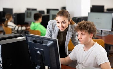 Fototapeta premium Positive female teacher tells a teenager how to work on a computer