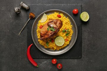 Plate of traditional chicken biryani with ingredients on black background