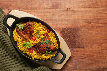 Baking dish of traditional chicken biryani on wooden background