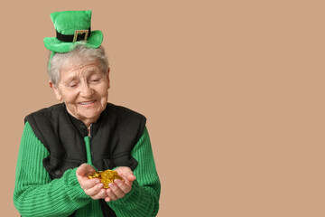 Senior woman in leprechaun hat with coins on brown background. St. Patrick's Day celebration