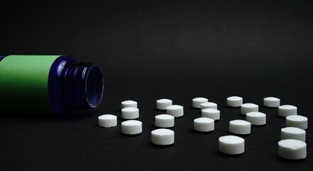 An amber glass pill bottle lying on its side with spilled tablets on a black background. A powerful concept of medicine, healthcare, and pharmaceutical themes.