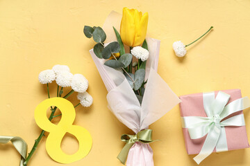 Mini bouquet of beautiful spring flowers in wrapping paper with figure 8 and gift box on yellow background. International Women's Day
