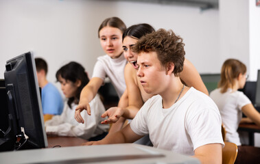 Multinational young students group working and emotionally discussing together in college computer room