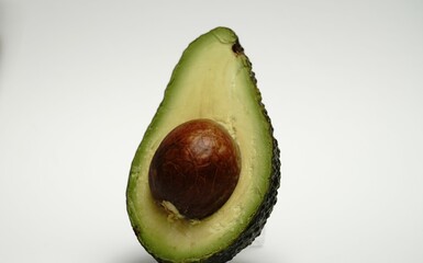 Halved avocado fruit. Seed exposed center. Smooth green flesh. White studio background.