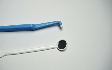Dental mirror tool. Blue interdental brush. White clean background. Oral care equipment.

