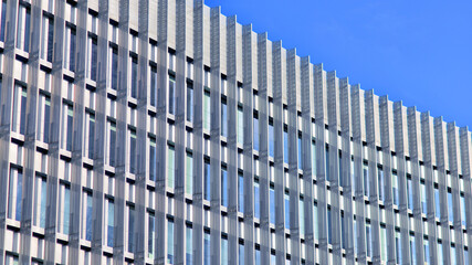 Geometric reflection: Partly cloudy sky reflected by window panes of office building. Surface of...