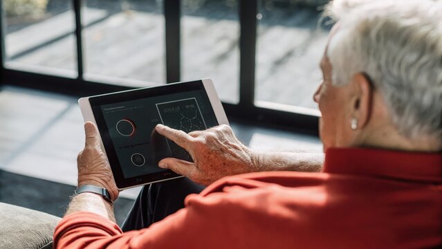 An elderly man uses a finger to rotate a holographic representation of his overall wellness stats the sleek interface surrounding him with an aura of soft light and data.