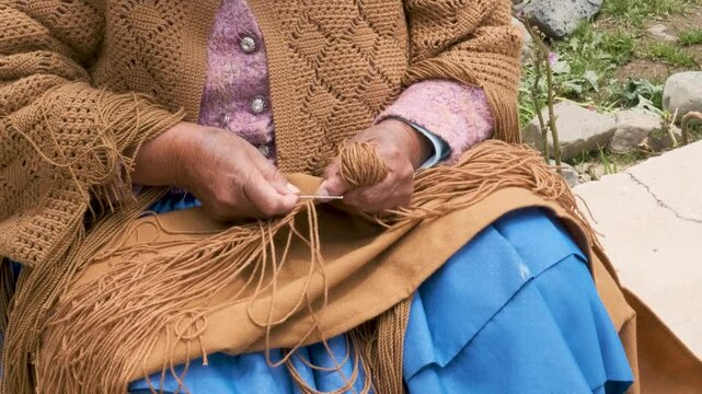 adult aymara woman in pollera working on handcrafted wool textiles at home - work concept