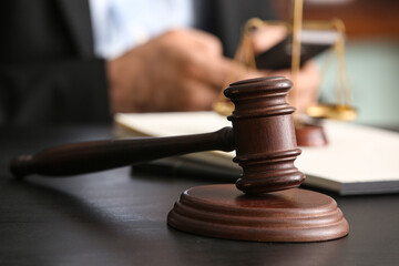 Judge's gavel on black table against male lawyer with mobile phone in office