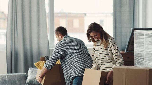 A couple is happily moving into their new home, surrounded by boxes and dreams for the future