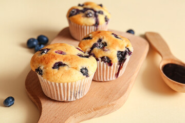 Wooden tray with tasty blueberry muffins on light background, closeup