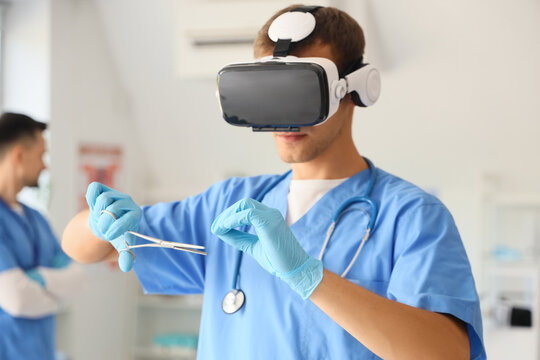 Male doctor with medical scissors using VR glasses in clinic
