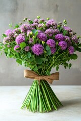 A minimalistic bouquet of wild herbs featuring vibrant purple flowers and green foliage, tied with a natural burlap ribbon