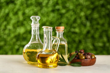 Decanters and bottle of fresh olive oil on white table outdoors