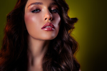 Fototapeta premium Close-up of a glamorous brunette woman in elegant makeup against a dark green background
