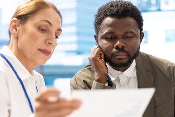 Diverse group of business associates meets to evaluate project updates, analyzing statistics and processes to accomplish company objectives. General manager meeting with employees.