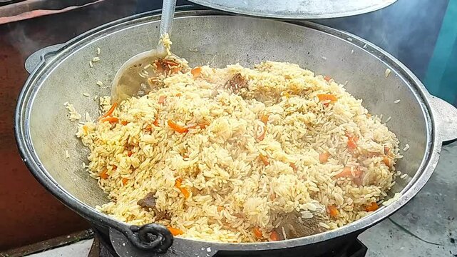 Uzbek pilaf cooked in a big pot outside . High quality FullHD footage