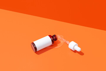 Cosmetic serum bottle with dropper on orange background. Minimalist image of dropper bottle mockup with space for design