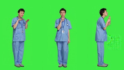 Obraz premium Medical assistant asking to keep quiet and be silent against greenscreen, showing hush mute symbol to keep privacy and silence. Young nurse showing secrecy taboo sign. Camera A.