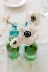 Elegant table decoration featuring fresh flowers in colorful glass vases at a gathering during the afternoon