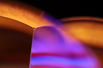 Orange and purple liquid reflections on dark background, scientific abstraction 