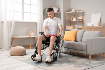 Sporty young man in wheelchair exercising with body roller at home