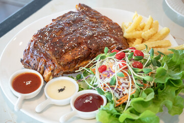 Pork rib steak served with vegetable salad and french fries