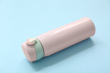 Modern pink thermos on blue background