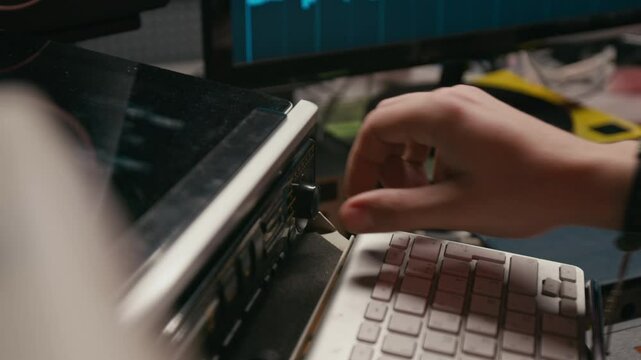 Closeup of hand of unrecognizable male musician wearing leather bracelet adjusting sound controls on equalizer console while setting up equipment for recording session in studio