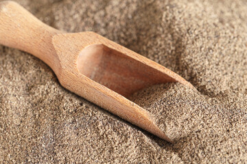 Wooden scoop with black pepper powder as background