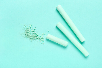 Green chalks with crushed pigment on turquoise background