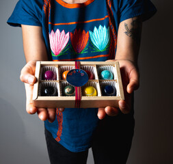 Pastry chef holding box of colorful handmade chocolates