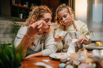 Mother and daughter tasting easter cookies in the kitchen