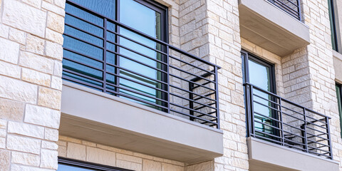 Balcony with metal railings, double glass patio doors. Exterior brick wall of apartment building house.  