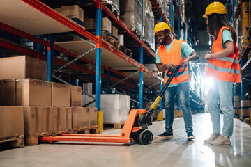 Warehouse workers using pallet jack and cardboard boxes on pallets