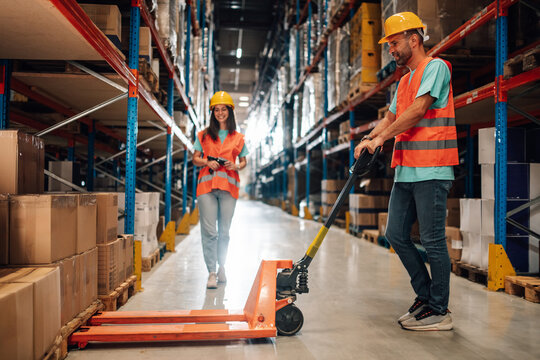 Warehouse workers managing inventory and logistics with hand pallet truck and scanner - Powered by Adobe