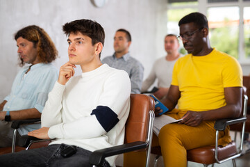 Small group of mature guys attending the lecture with concern sitting on chairs in light room