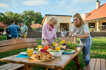 Happy family preparing food on table in backyard for garden party celebration