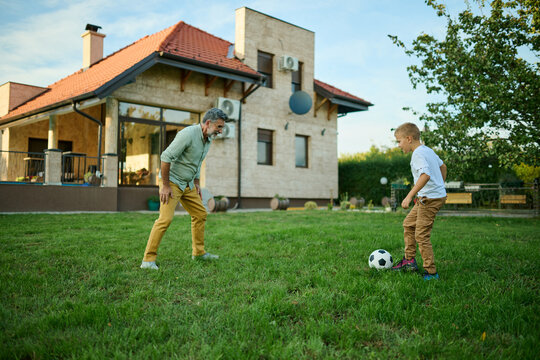 Grandfather and grandson playing soccer in the backyard